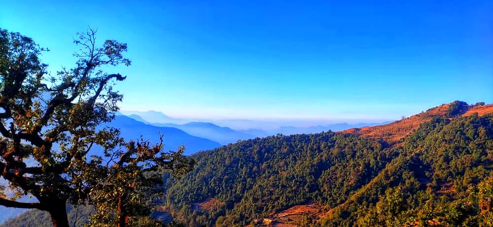 Layered Himalayan panorama with receding ridgelines and valleys fading into blue-grey mist, high altitude Uttarakhand