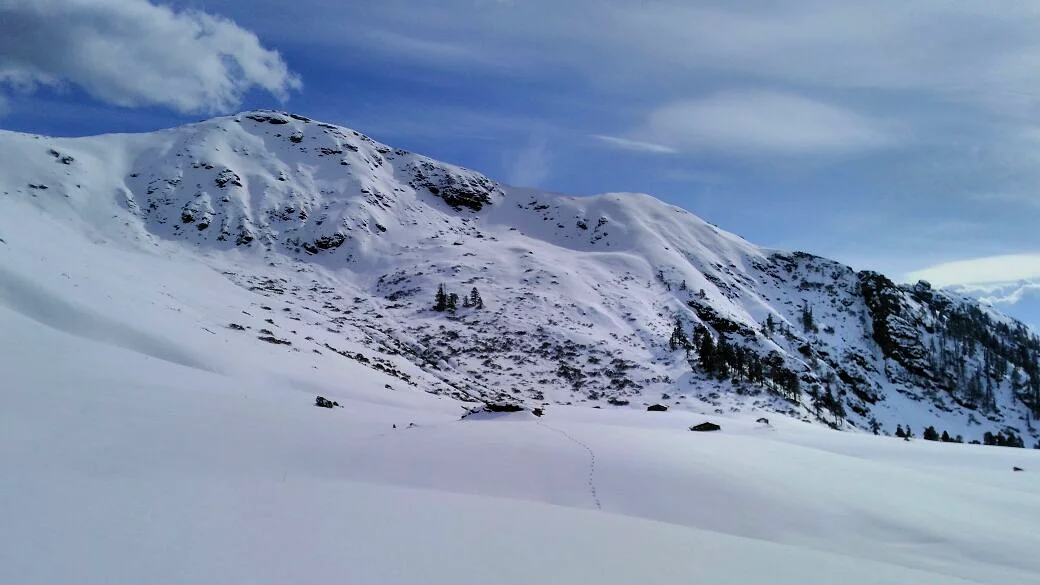 Lone set of footprints crossing a vast snowfield towards a Himalayan summit, showing the journey ahead